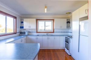 Una cocina con gabinetes blancos y encimera. en Berrara Cove Beach House, en Berrara 8 fotos más