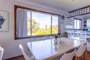 Un comedor con una mesa y un gran ventanal. en Berrara Cove Beach House, en Berrara