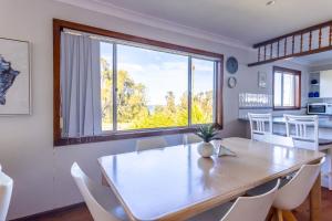 a dining room with a table and a large window at Berrara Cove Beach House in Berrara