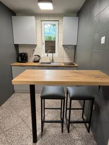 a kitchen with a wooden table and two stools at Domek Jezioro Białe Okuninka Centrum 250m molo in Okuninka