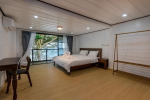 a bedroom with a bed and a desk and a piano at Beach House Pool Villa in Nakhon Si Thammarat