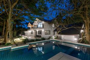 a swimming pool in front of a house at night at Beach House Pool Villa in Nakhon Si Thammarat