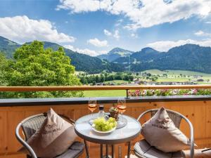 - une table avec des verres à vin sur un balcon avec des montagnes dans l'établissement Bauernhof Mühlbichl, à Söll