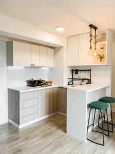 a kitchen with white cabinets and green bar stools at Miraflores House C&F in Lima