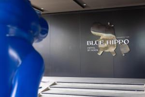 a person standing in front of a wall with a blue hippo sign at Blue Hippo Hotel in Ban Khlong Samrong
