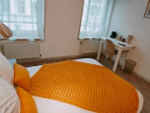 ein Schlafzimmer mit einem Bett mit einer orangefarbenen Decke in der Unterkunft Le Royal Hôtel in Saint-Pol-sur-Ternoise