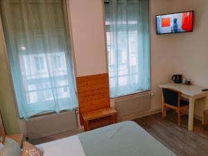 a bedroom with two windows and a desk and a television at Le Royal Hôtel in Saint-Pol-sur-Ternoise