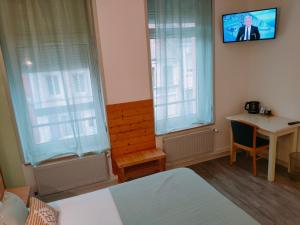 Habitación con cama, mesa y TV. en Le Royal Hôtel, en Saint-Pol-sur-Ternoise