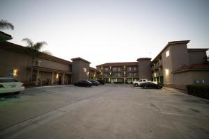 un estacionamiento con autos estacionados frente a un edificio en Mid City Inn & Suites Pico Rivera en Pico Rivera