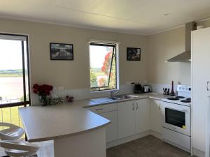 a kitchen with white cabinets and a counter top at Peaceful Riverfront cottage in small northland town in Te Kopuru