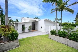 a white house with palm trees and grass at Stunning Mooloolaba Waterfront Home -10 guests ZB1 in Mooloolaba