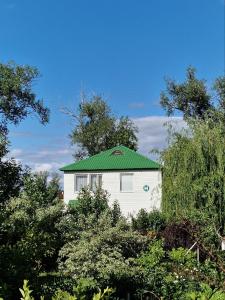 a white building with a green roof with trees at PARK HOTEL Uralsk in Uralsk