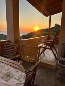 un balcón con mesas, sillas y una puesta de sol en Gavrilis Apartments, en Nénita