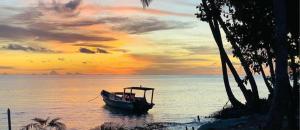 ein Boot, das bei Sonnenuntergang auf dem Wasser sitzt in der Unterkunft Hollow trees Mentawai HTS Surf camp Katiet front Hollow tree,Lance Right,Lance right,Bintang wave in Katiet
