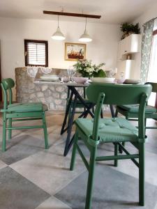 a dining room with green chairs and a table at Holiday Home Bukovac in Klimno