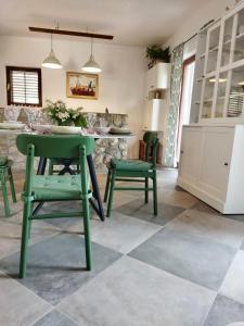 a kitchen with green chairs and a table and a counter at Holiday Home Bukovac in Klimno