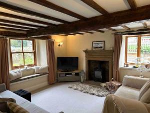 a living room with a tv and a fireplace at Church Farm Cottage Fritchley in Crich