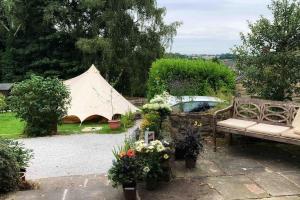 a tent in a garden with a bench and flowers at Church Farm Cottage Fritchley in Crich