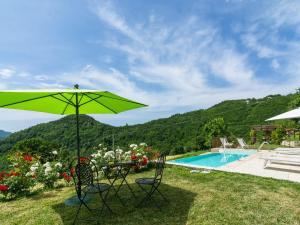a green umbrella and chairs next to a swimming pool at Beautiful Apartment in Sestino with Garden in Sestino