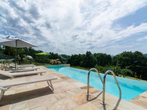 a swimming pool with chairs and an umbrella at Beautiful Apartment in Sestino with Garden in Sestino
