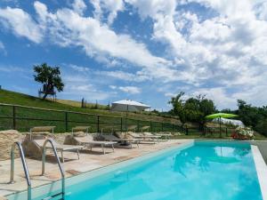 ein Pool mit Stühlen und Sonnenschirmen neben einem Zaun in der Unterkunft Beautiful Apartment in Sestino with Garden in Sestino