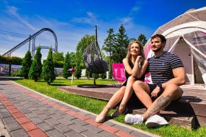 a man and a woman sitting next to a roller coaster at Holiday Park Zator in Zator