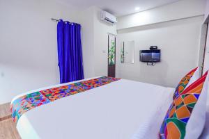 1 dormitorio con cama blanca y manta colorida en FabExpress Sanva, Pallikaranai en Chennai