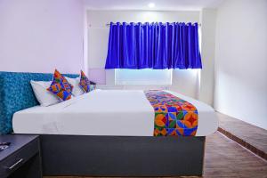 1 dormitorio con 1 cama grande y cortinas moradas en FabExpress Sanva, Pallikaranai, en Chennai