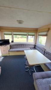 a living room with a couch and a table in a caravan at Letniaczki ABI in Rydzewo