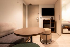 東京的住宿－karaksa hotel colors Tokyo Yaesu，客厅配有桌子和沙发