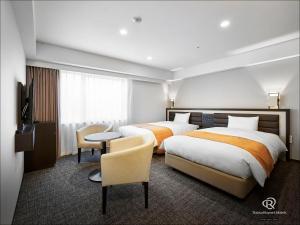 a hotel room with two beds and a table and chairs at Daiwa Roynet Hotel Osaka-Kitahama in Osaka +86 photos