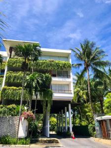 a building with palm trees in front of it at Beachfront 2 BR Luxury Condo Chava Surin in Surin Beach
