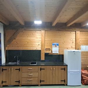 a kitchen with wooden cabinets and a white refrigerator at Glamping - Kamp Steska in Žalec