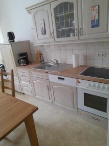 a kitchen with white cabinets and a sink and a table at 70 qm Ferienwohnung mit 2 Schlafzimmern in Zwickau