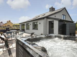 a hot tub on a patio with a house at Rhiwmynach in Aberystwyth