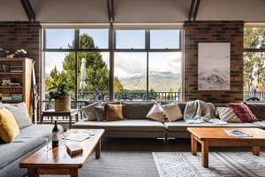 a living room with a couch and tables and windows at Myee Alpine Retreat in Mount Beauty