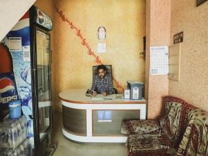 un hombre sentado en un mostrador en una tienda en OYO 45569 Goyal's Inn, en Ajmer