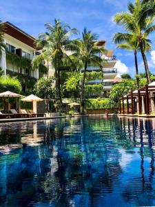 una piscina di fronte a un edificio con palme di Beachfront 2 BR Luxury Apartment Chava Surin a Surin Beach