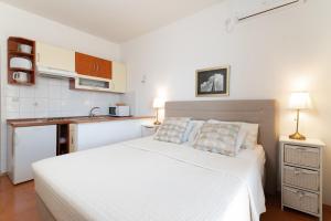 um quarto com uma cama branca e uma cozinha em Apartments Rozelyn em Ugljan