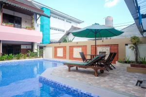 uma piscina com uma mesa e cadeiras e um guarda-sol em RedDoorz @ Mantrijeron 2 em Yogyakarta