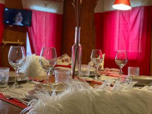 una mesa con copas de vino y un jarrón en ella en Alpine Majestic Escape - Balcone sulle Piste di Sci, en Champoluc