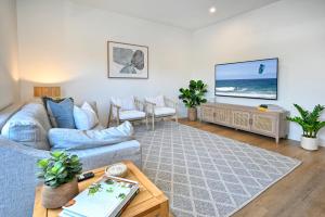 a living room with a blue couch and a tv at Stylish, Beachside 4 b/r Dream Home - 8 guests ZD7 in Kawana Waters