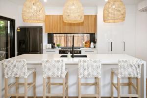 une cuisine avec un grand îlot blanc et des tabourets dans l'établissement Stylish, Beachside 4 b/r Dream Home - 8 guests ZD7, à Kawana Waters