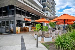 un restaurant avec des parasols orange en face d'un bâtiment dans l'établissement Stylish, Beachside 4 b/r Dream Home - 8 guests ZD7, à Kawana Waters