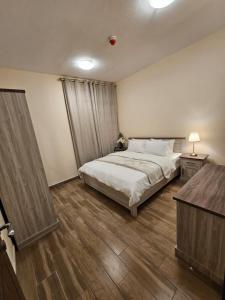 a bedroom with a bed and a wooden floor at Modern & Cozy 1 Bedroom and 1 Living Room Apartment near Sharjah University in Sharjah