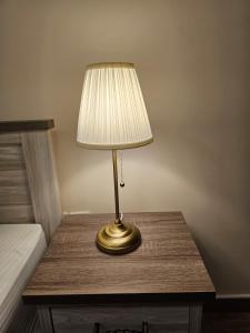 a lamp sitting on a table next to a bed at Modern & Cozy 1 Bedroom and 1 Living Room Apartment near Sharjah University in Sharjah