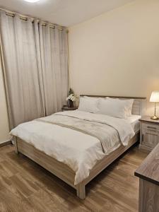 a bedroom with a large bed with white sheets at Modern & Cozy 1 Bedroom and 1 Living Room Apartment near Sharjah University in Sharjah