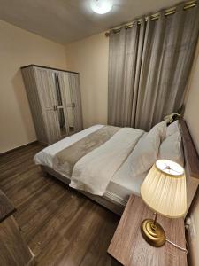 een slaapkamer met een bed en een tafel met een lamp bij Modern & Cozy 1 Bedroom and 1 Living Room Apartment near Sharjah University in Sharjah