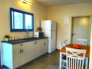 een keuken met een witte koelkast en een tafel bij Bein Tavor Lekineret- quiet cabin in Neve Ilan in Sede Ilan