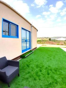 een huis met een groene tuin met een bank bij Bein Tavor Lekineret- quiet cabin in Neve Ilan in Sede Ilan